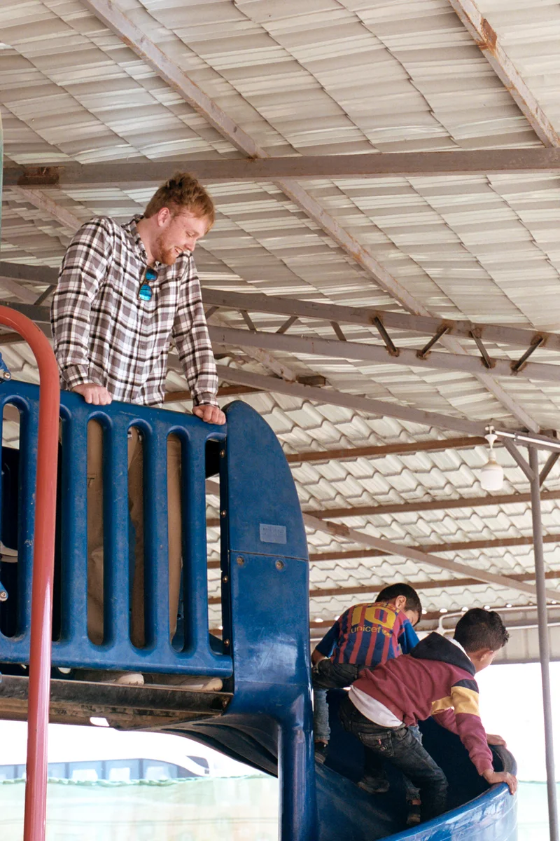 Roots for Refugees volunteer standing on a slade with Azraq Center students.